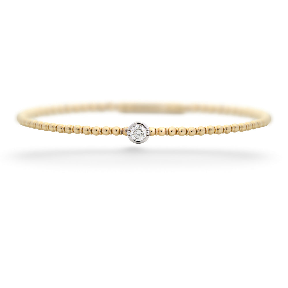 Gold bracelet with a small diamond on a white background Diamond Beaded Bangle