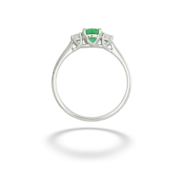 A silver ring featuring a central green heart-shaped emerald-cut gemstone and two small clear accent stones on either side, shown against a plain white background with a soft shadow below. Emerald and Diamond Ring