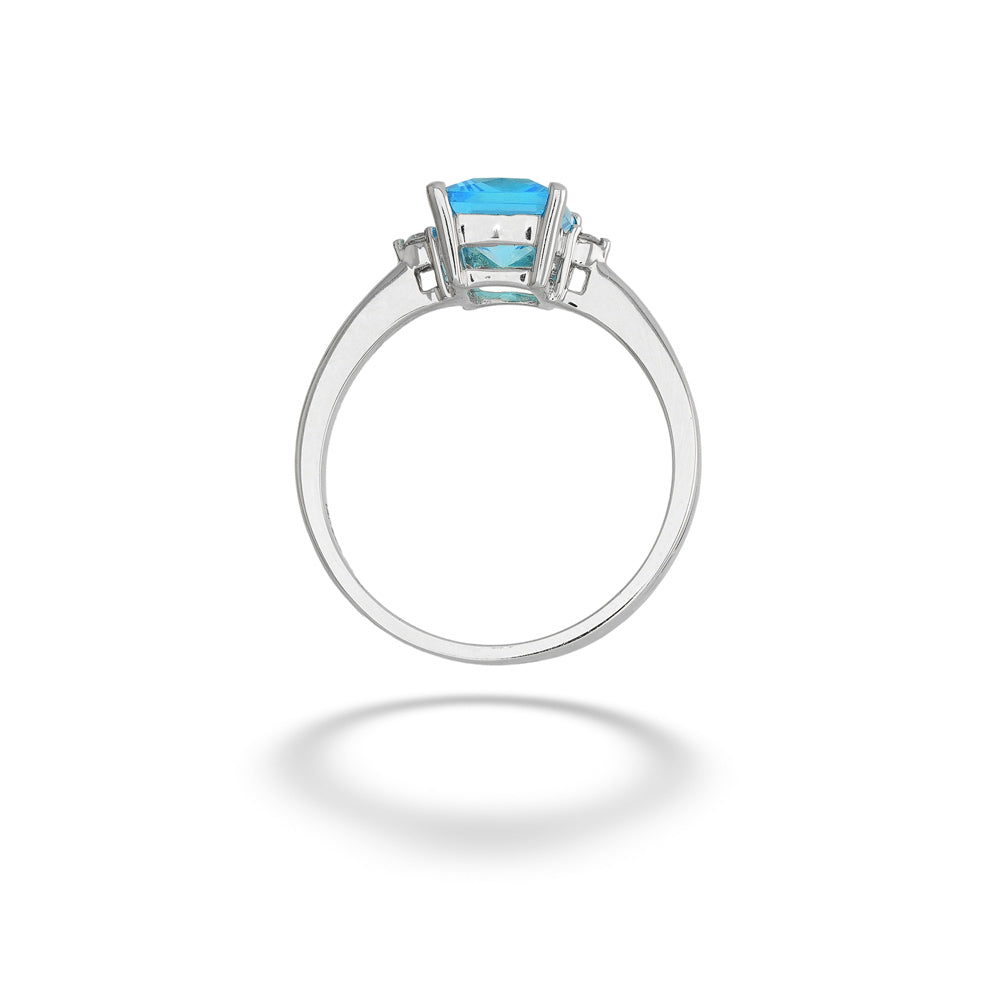 A silver ring featuring a square-cut light blue gemstone in a prong setting, shown against a plain white background with a soft shadow below. Blue Topaz and Diamond Ring