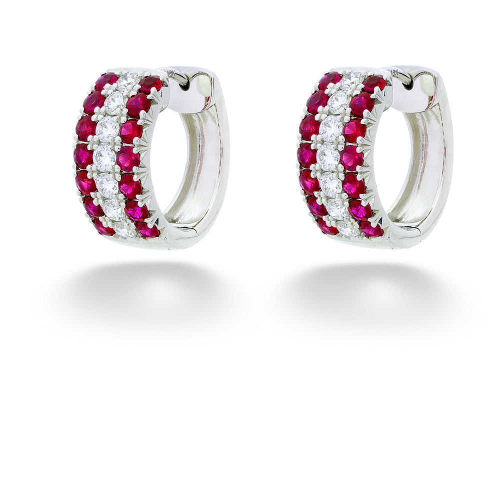 Pair of silver hoop earrings with red gemstones on a white background Ruby and Diamond Huggie Earrings