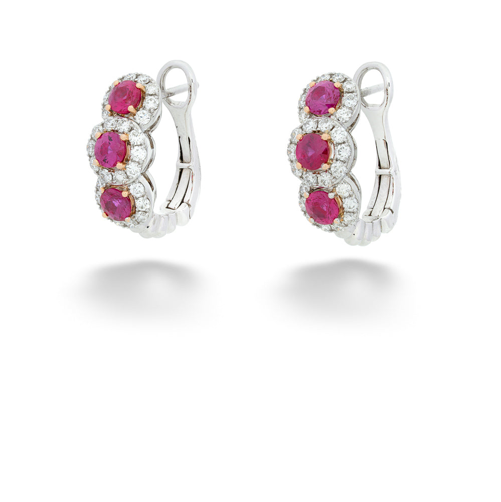 Pair of silver hoop earrings with red gemstones on a white background 3-Stone Ruby and Diamond Huggie Earrings