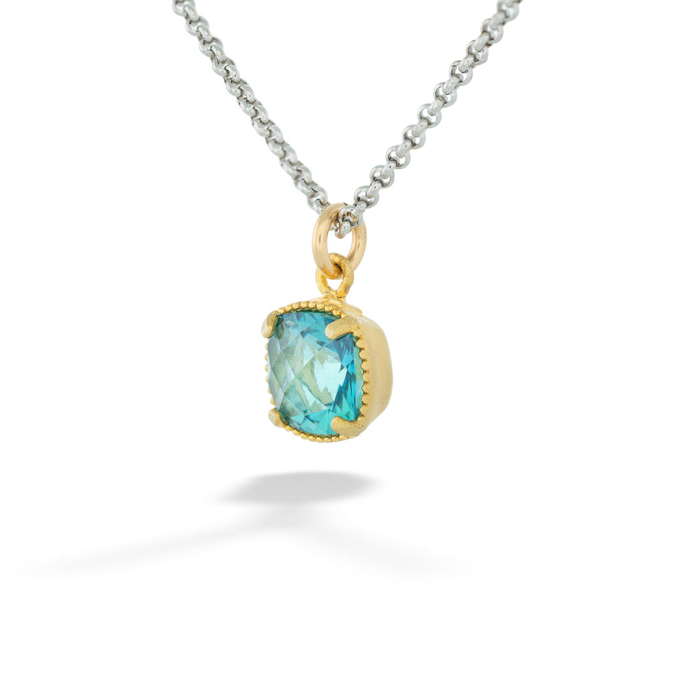Gold pendant with a blue gemstone on a silver chain against a white background Topaz Pendant Necklace by Anatoli