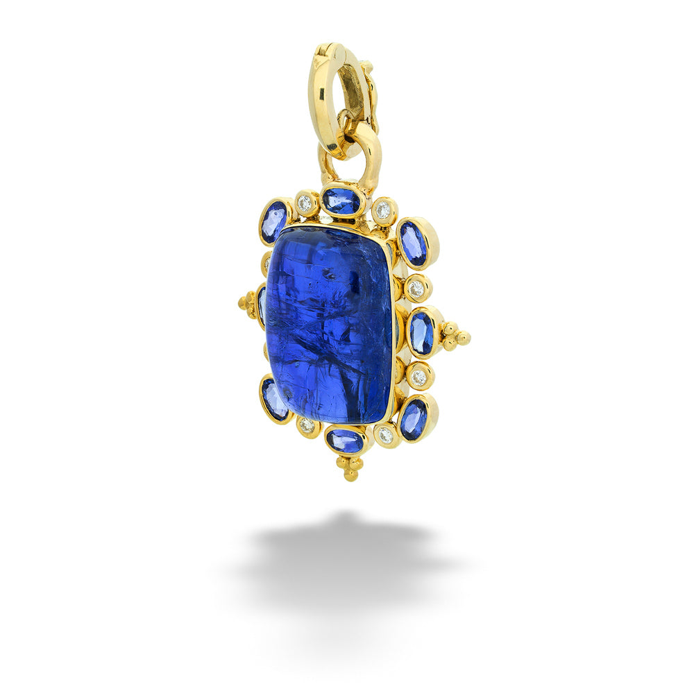 Gold pendant with a blue gemstone on a white background Cabachon Tanzanite Pendant with Diamond and Tanzanite Halo by Mazza