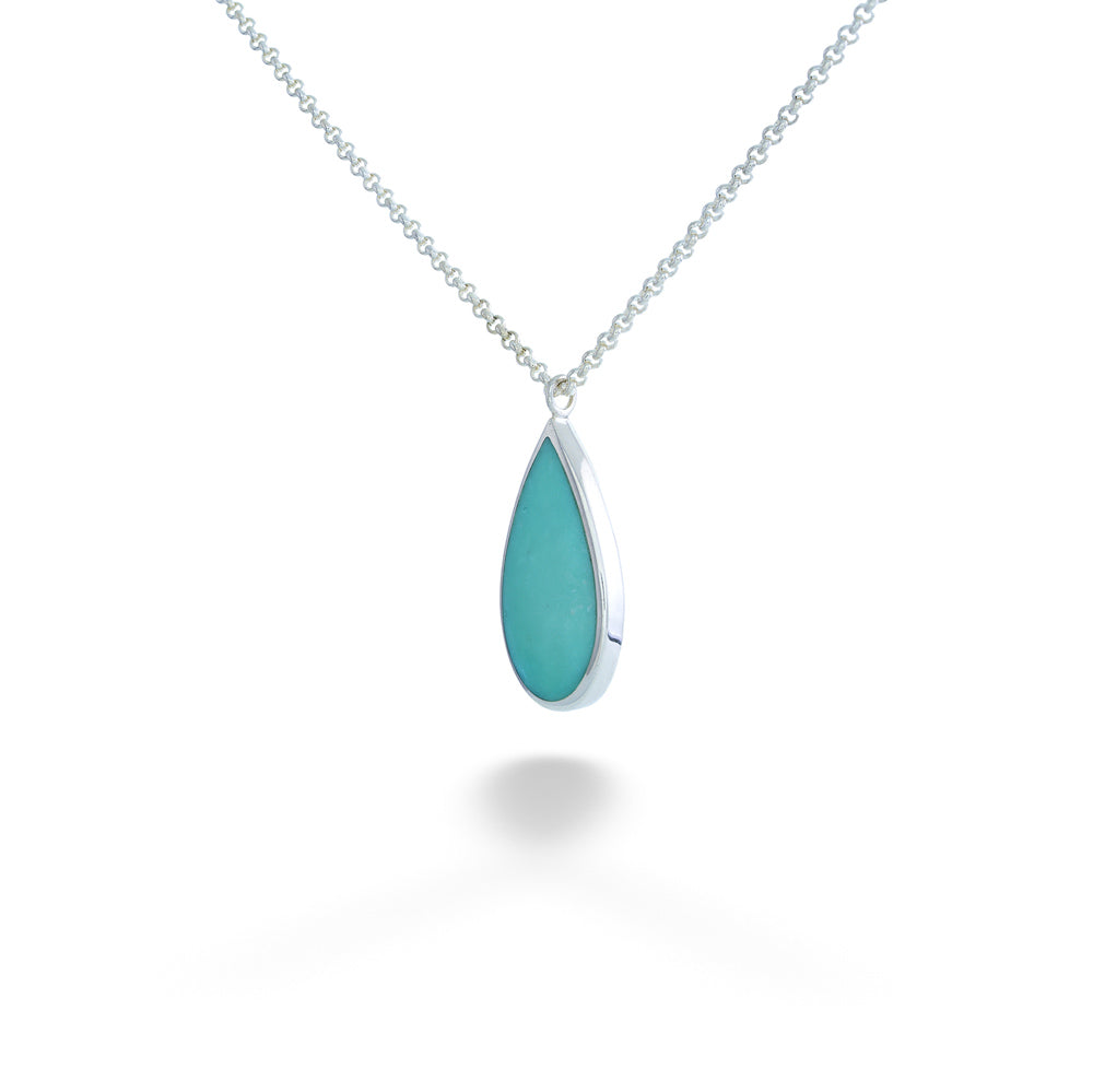 Teardrop-shaped turquoise pendant on a silver chain against a white Turquoise Drop Pendant Necklace by Acleoni background