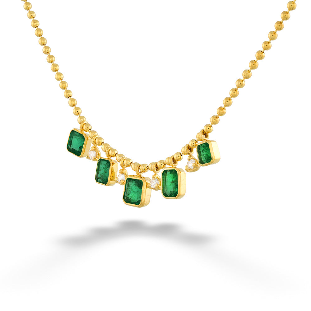 Gold necklace with emerald green gemstones on a white background Dangling Emerald and Diamond Necklace by Mazza