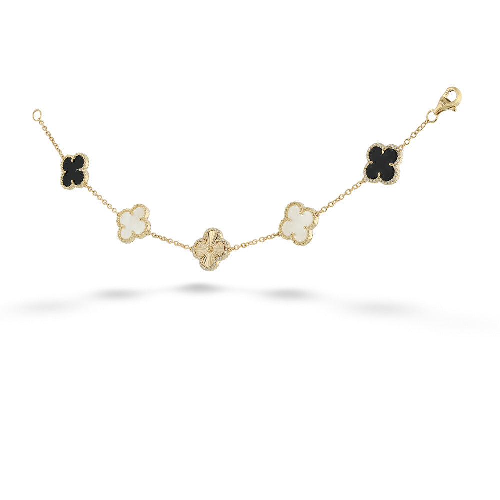 A gold chain bracelet featuring five clover motifs in different colors: three black, one milky white, and one gold. The center clover is paved with small clear stones. angled.