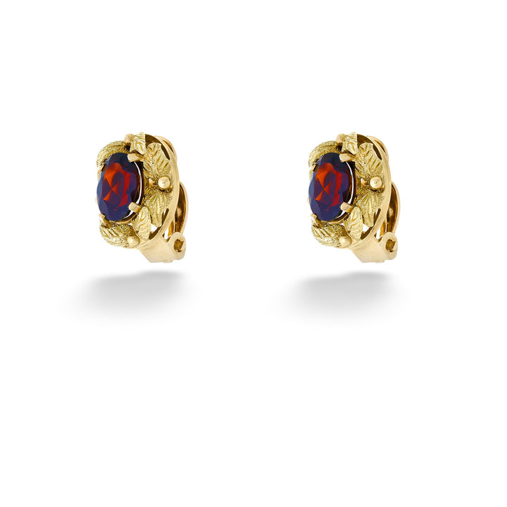 Gold earrings with red stones on a white background Oval Garnet Earrings with Leaf Accents