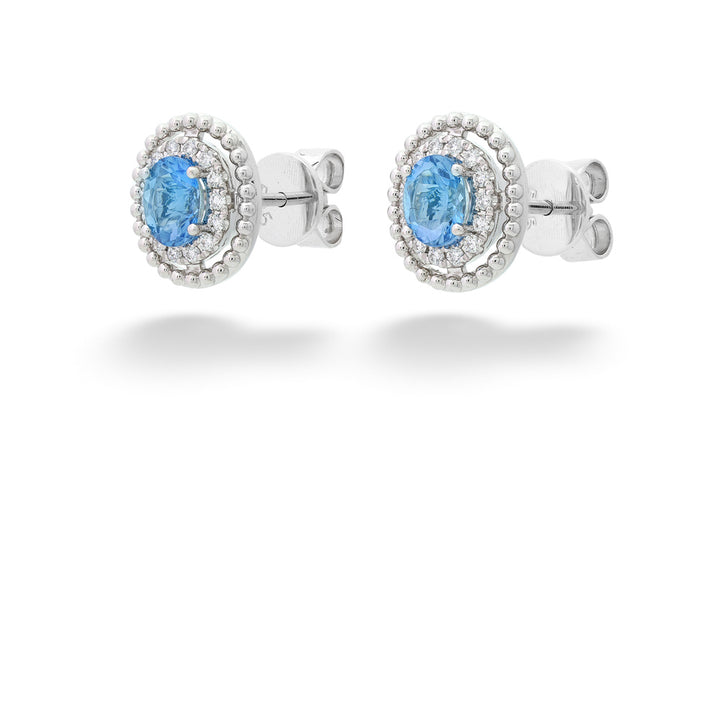 Pair of silver earrings with blue gemstones on a white background Aquamarines with Diamond Halo Beaded Edges Stud Earrings