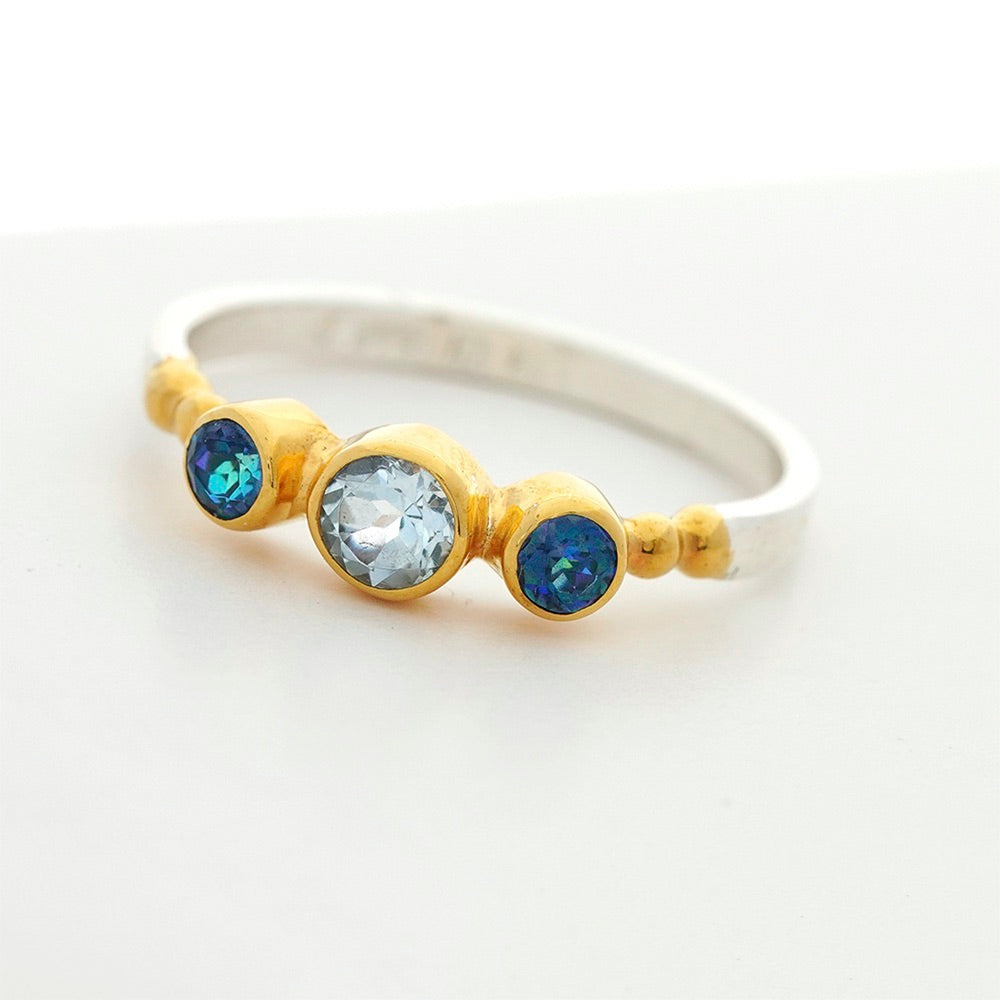Ring with gold band and three gemstones on a white background Gold Vermeil Blue Topaz Ring by Michou