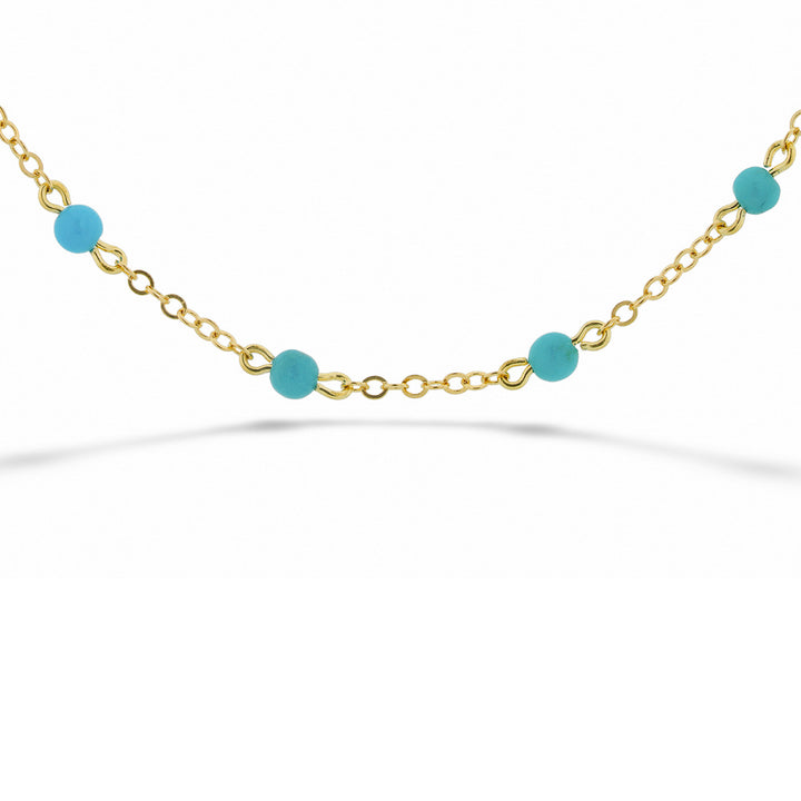 Gold bracelet with blue beads on a white background  14K Yellow Gold Chain and Turquoise Bead Bracelet 