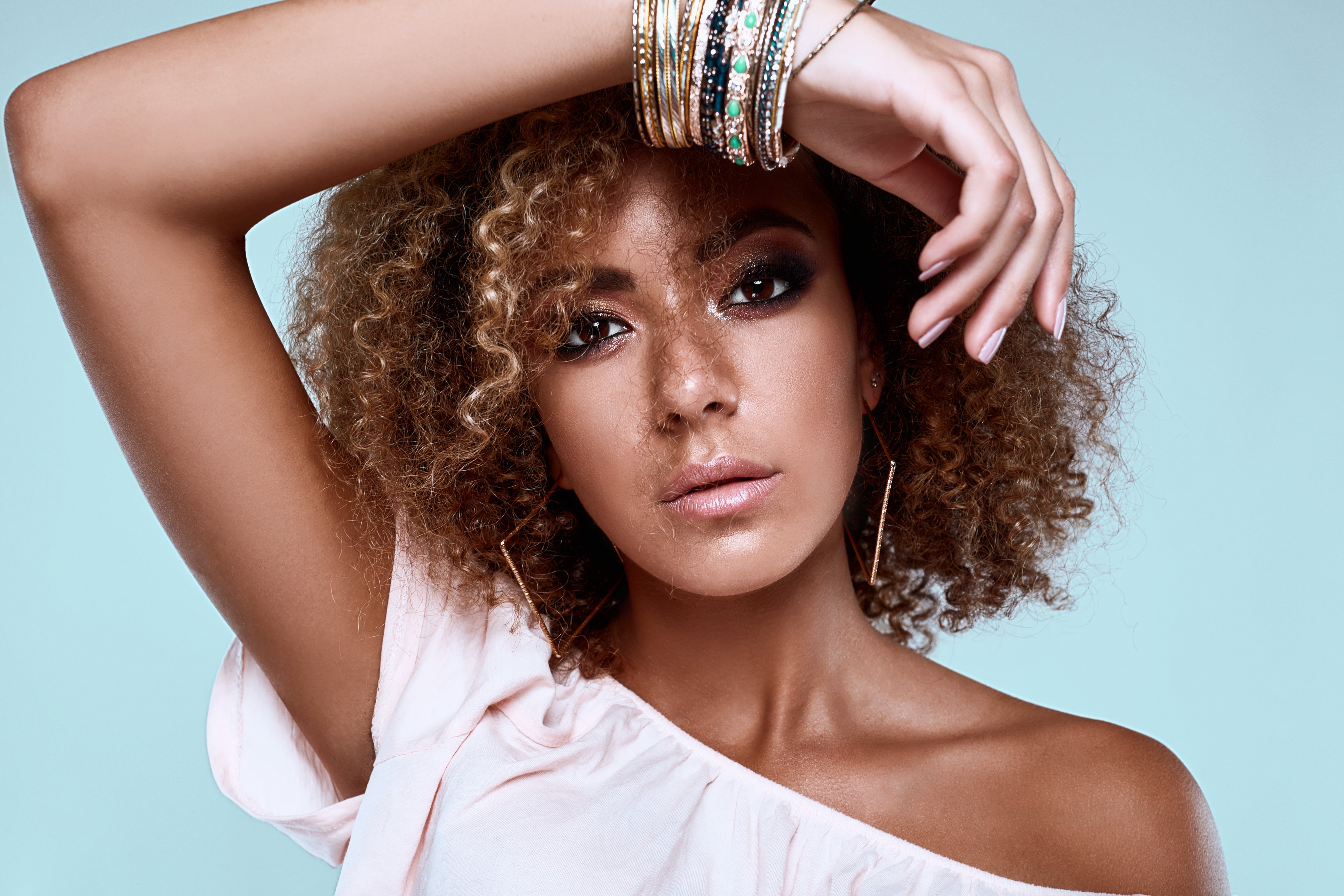 a woman with curly hair wearing stacked bracelets saying what jewelry the gem collection is loving