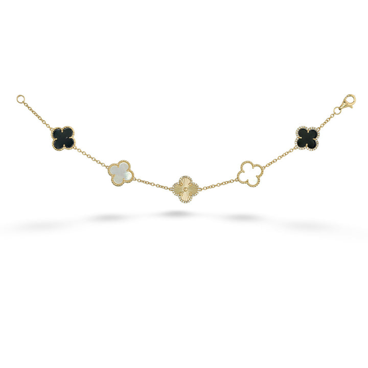 A gold chain bracelet featuring five clover motifs in different colors: three black, one milky white, and one gold. The center clover is paved with small clear stones.